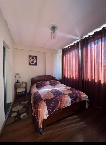a bedroom with a bed and a window with curtains at Hostal Graciela in Oruro
