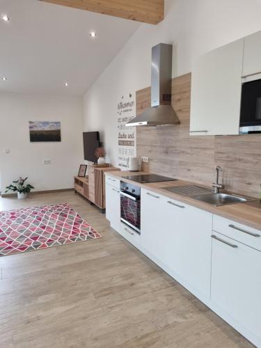 a kitchen with white cabinets and wooden floors at Eiselehof Ferienwohnungen in Alleinlage in Rot am See