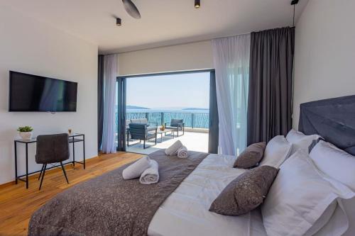 ein Schlafzimmer mit einem großen Bett mit einem großen Fenster in der Unterkunft Beachfront Villa Sol&Mar with heated pool and jacuzzi in Kaštela