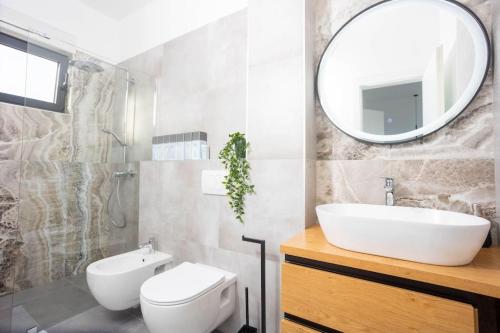 ein Badezimmer mit Waschbecken, Toilette und Spiegel in der Unterkunft Beachfront Villa Sol&Mar with heated pool and jacuzzi in Kaštela