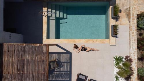 a woman laying on the floor next to a swimming pool at Pnoes Luxury Suites in Paliouri