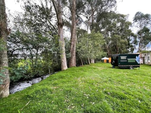 a rv parked in a field next to a stream at Yarumo Camper Trailer in Guasca