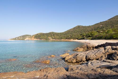 a sandy beach with rocks in the water at Residence Helios in Cargèse