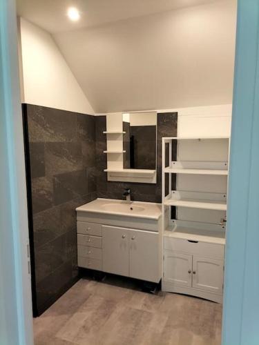 ein weißes Badezimmer mit einem Waschbecken und einem Spiegel in der Unterkunft Appartement pour 4prs dans maison individuelle in Allemont