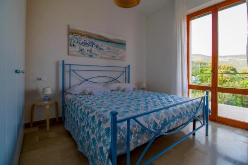 a blue bed in a room with a window at La terrazza - By Ligooria in Pietra Ligure