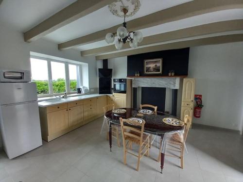 une cuisine avec une table, des chaises et un réfrigérateur dans l'établissement Gîte Au Soleil des Noës, à Courtils