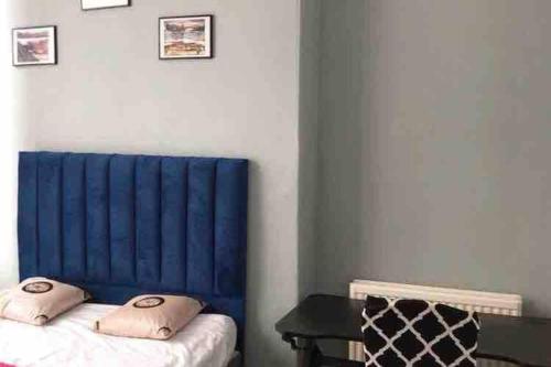 Habitación con cama con cabecero azul y mesa. en Grange Lone entire apartment with two double beds, en Edimburgo