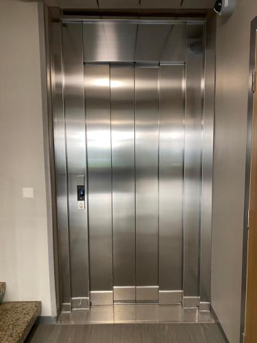 un ascensor en un edificio con una puerta de metal brillante en kauppalankatu kolmio, en Kouvola