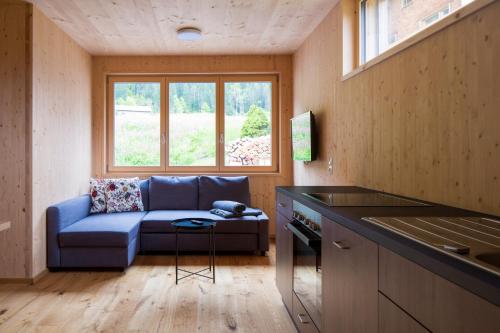 a living room with a blue couch and a window at Bergreich Appartement 1 in Schoppernau