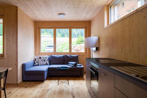 ein Wohnzimmer mit einem blauen Sofa und einem Tisch in der Unterkunft Bergreich Appartement 1 in Schoppernau