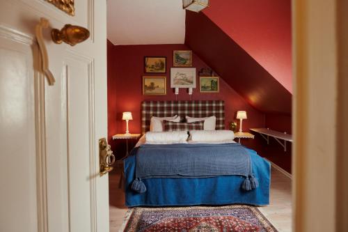 a bedroom with a bed with a red wall at Hotell Bäckagården in Ystad