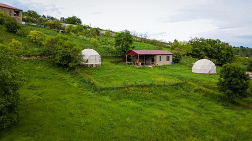 two white domes on a green hill with a house at Yenokavan Glamping in Ijevan