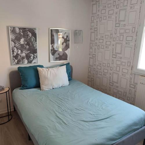 um quarto com uma cama com lençóis azuis e uma almofada em Home City House confort em Entrevennes