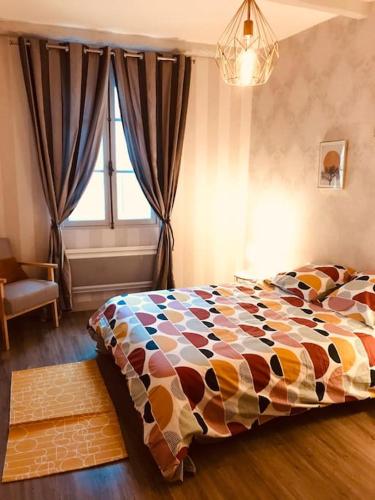 une chambre avec un lit avec une couette colorée et une fenêtre dans l'établissement Maison Face aux Remparts, à Aigues-Mortes