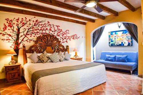 a bedroom with a large bed with a tree on the wall at Hotel Ana Catalina and Suites in San Miguel de Allende