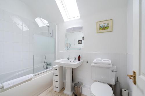 Baño blanco con lavabo y aseo en Mansewood Country House en Lochearnhead