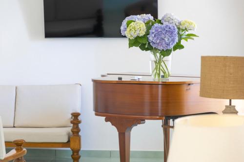 a vase of flowers on a table next to a chair at Hotel La Luna in Ischia
