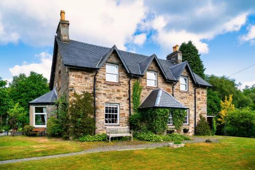 a stone house with a bench in front of it at Mansewood Country House in Lochearnhead