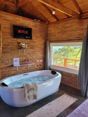 uma grande banheira num quarto com uma parede de tijolos em Chalés Bela Vista em São Thomé das Letras
