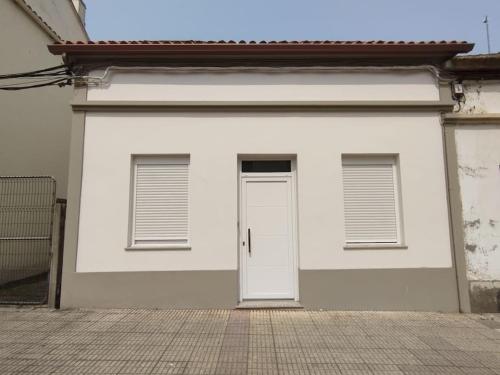 a white garage with a door and two windows at Areas Negras. Casas de Fanego. in Cariño