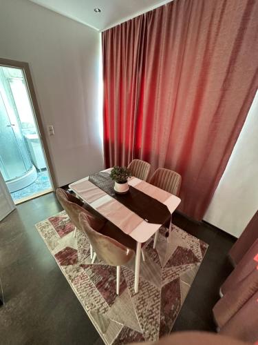 a dining room table with chairs and a red curtain at Modern Apartment Sarajevo in Sarajevo