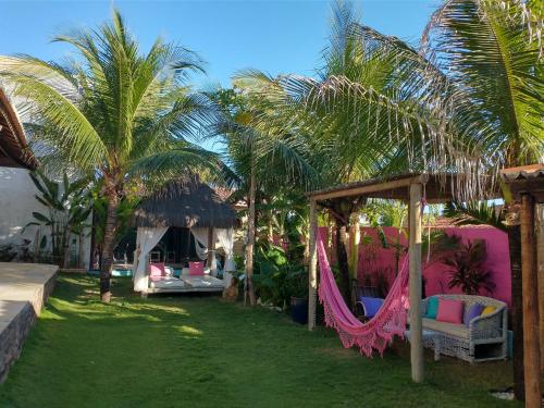 a resort with hammocks and palm trees in a yard at Vila Beija-flor in Canoa Quebrada
