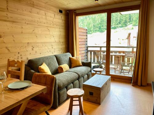 a living room with a couch and a table at Appartement rénové 2 chambres vue pistes parking privatif in Les Orres