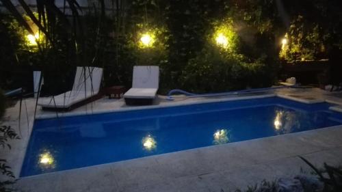 a swimming pool at night with two chairs and lights at CABAÑAS VILLA CLUB 4 cerca del aeropuerto el palomar in Hurlingham