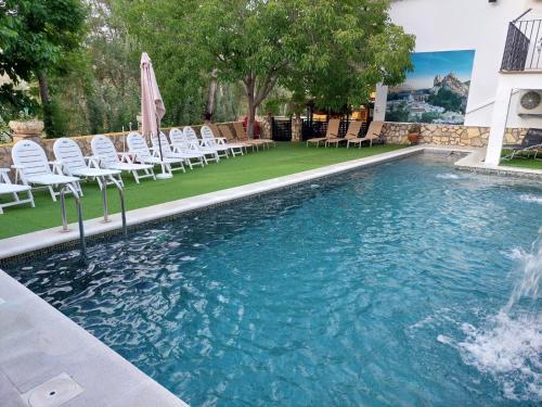 una piscina con sillas blancas y una fuente en Casa el angel, en Castril