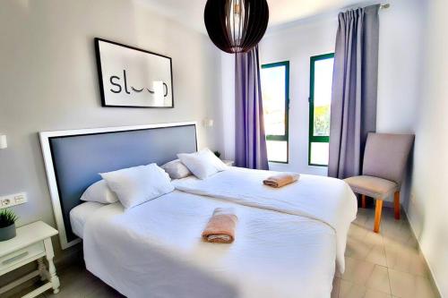 1 dormitorio con 1 cama blanca grande y toallas. en Cactus, Playa Y piscina, en Costa Teguise