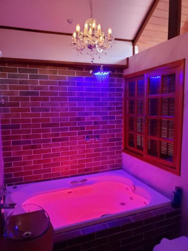 a bathroom with a pink tub with a brick wall at Mansão Austríaca Guesthouse in Campos do Jordão