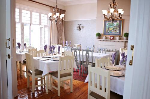 a dining room with white tables and chairs and a chandelier at Oleander Guest House in Kimberley