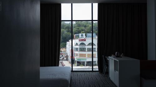 ein Schlafzimmer mit einem großen Fenster mit einem Bus nach draußen in der Unterkunft Beverly Hotel in Taiping