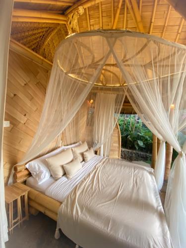 a bedroom with a bed with a canopy at Wahem Eco Bamboo - Wahem Tebenan in Ubud