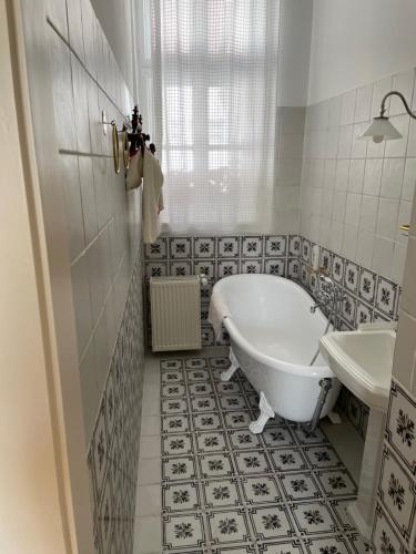 a white bathroom with a tub and a sink at Hajós-ház in Szeged