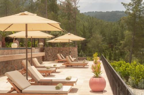 een groep stoelen en parasols op een patio bij IZZ Getaway - Adults Only in Göcek