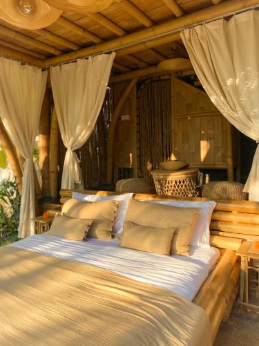 a bed with white sheets and pillows in a room at Wahem Eco Bamboo in Ubud