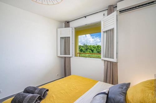 Schlafzimmer mit einem Bett und einem Fenster in der Unterkunft Navira - Appartement le Pavillon in Le Lamentin