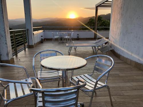 a table and chairs on a balcony with the sunset at Statera Hotel Village in Poderia