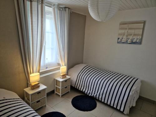 two beds in a room with two lamps and a window at Gîte la crinière au vent in Étréaupont