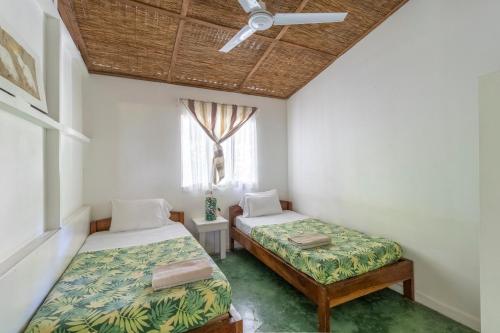 a bedroom with two beds and a window at Bajo el Arbol B&B in Santa Teresa Beach