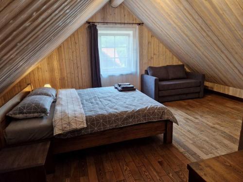 ein Schlafzimmer mit einem Bett und einem Stuhl im Dachgeschoss in der Unterkunft Anykščiai MĖNULIO AKMUO 