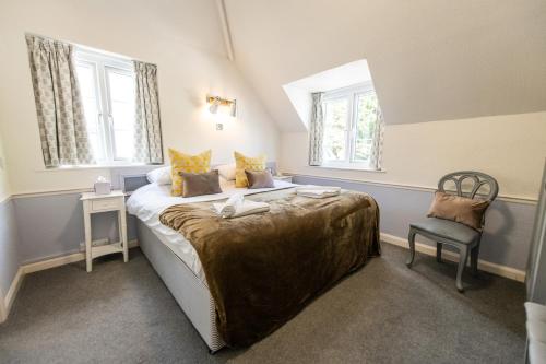 a bedroom with a large bed with a chair and two windows at The Woodlands Hotel in Sidmouth