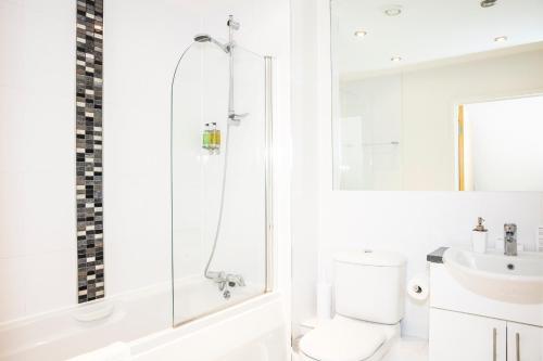 a white bathroom with a shower and a toilet at Oakdale Apartments in Woking