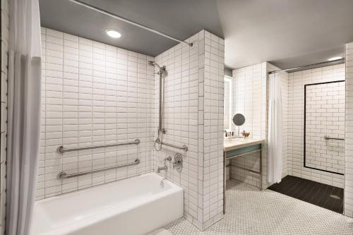 a white bathroom with a tub and a sink at Hotel Northland, Autograph Collection in Green Bay