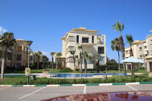 un edificio con palme di fronte a un parcheggio di Appt 22 Bloc G- Hicherraton plage Residence Bella Vista, BOUZNIKA BAY a Skhirat