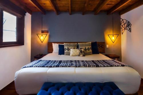 a bedroom with a large white bed with blue pillows at Hotel Kali in Tapalpa