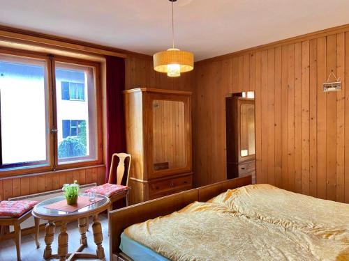 1 dormitorio con 1 cama y 1 mesa en Chasa Sassalbo, en Poschiavo