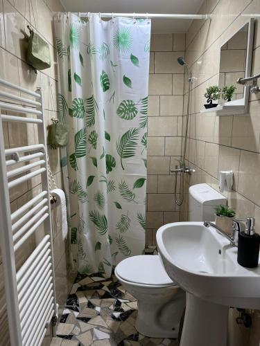 a bathroom with a shower curtain with a toilet and a sink at Cabana Muntelui in Munteni