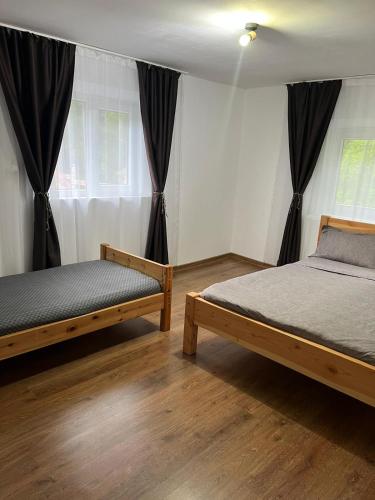 two beds in a bedroom with black curtains at Cabana Muntelui in Munteni